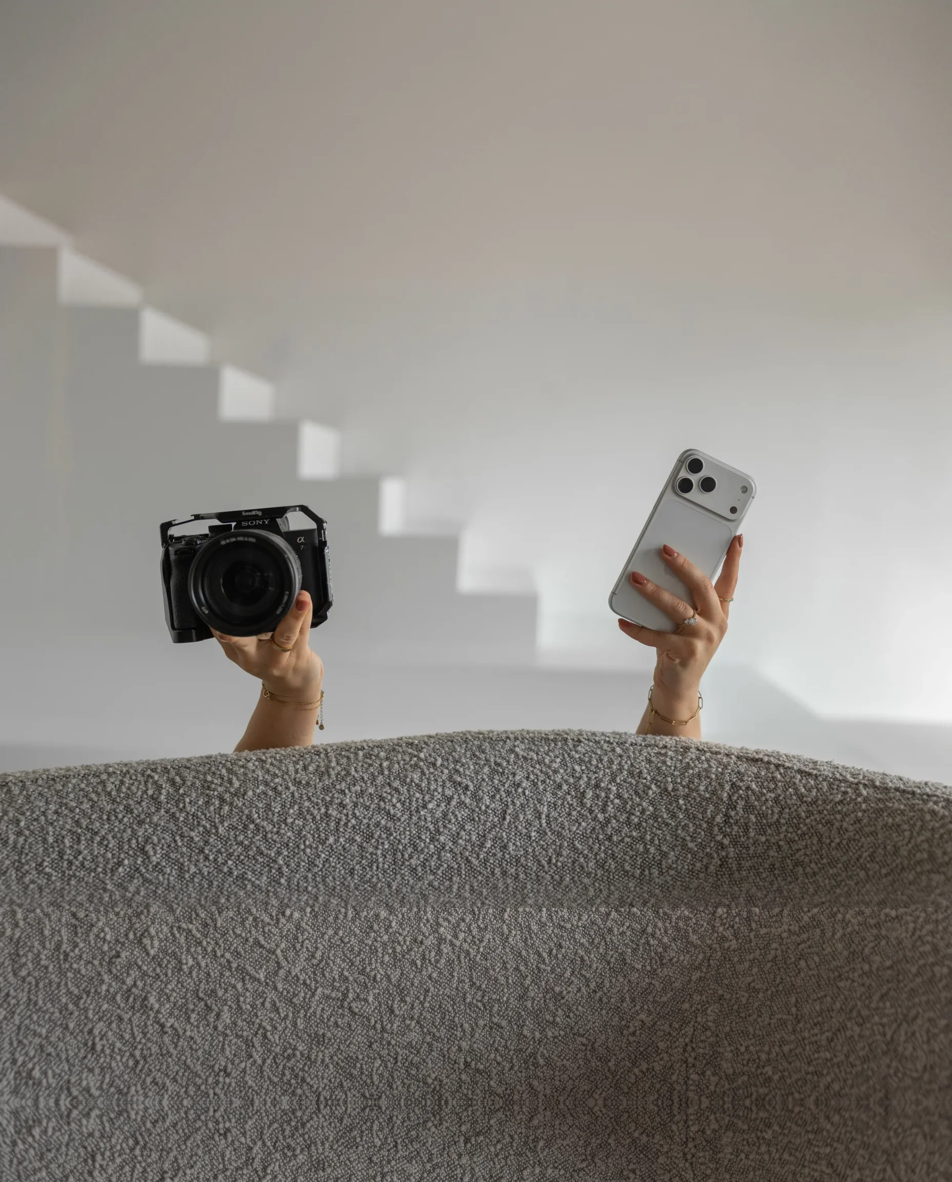 Vienna houdt haar camera en telefoon omhoog achter de bank